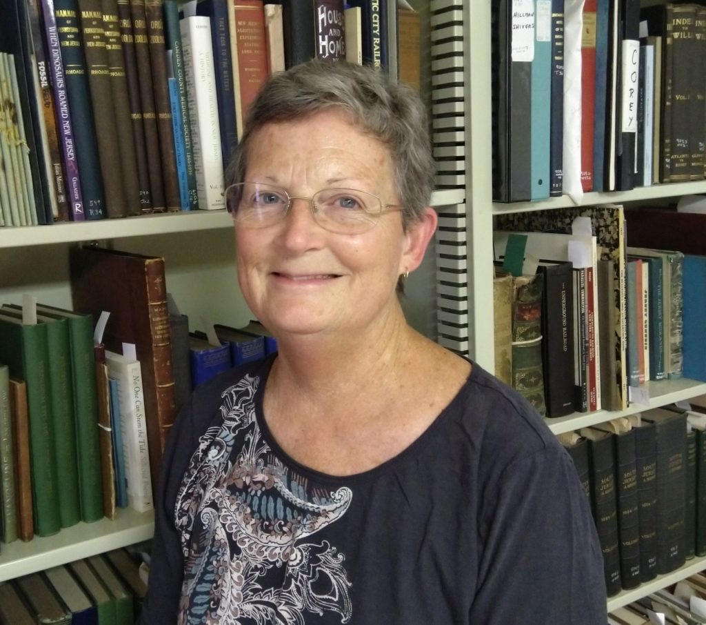Photo of Melinda McGough standing in front of bookshelves