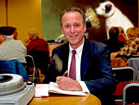 Fred Barnum sitting at a table, signing a book